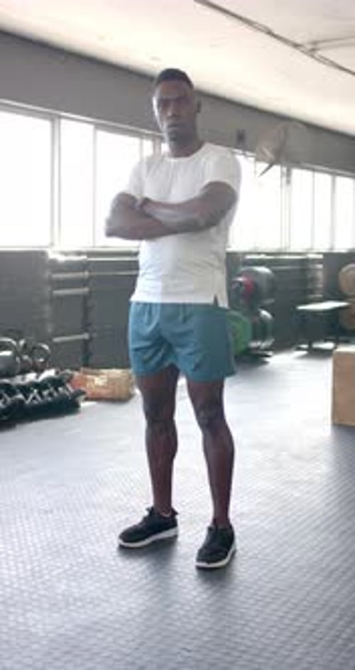 Vertical video: Standing in gym, man in athletic wear crossing arms, looking confident