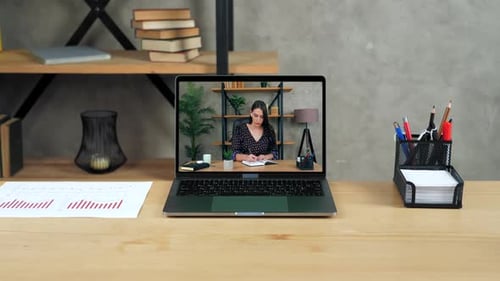 Laptop Standing on Table Display with Businesswoman in Office Writes in Notebook