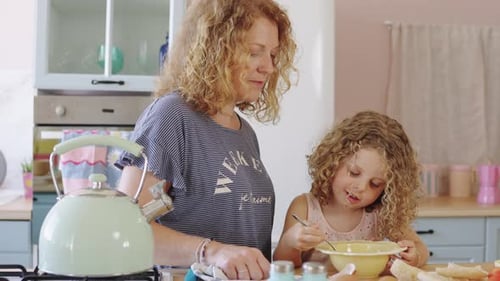 Mother and Daughter in Bright Kitchen Eating Breakfast