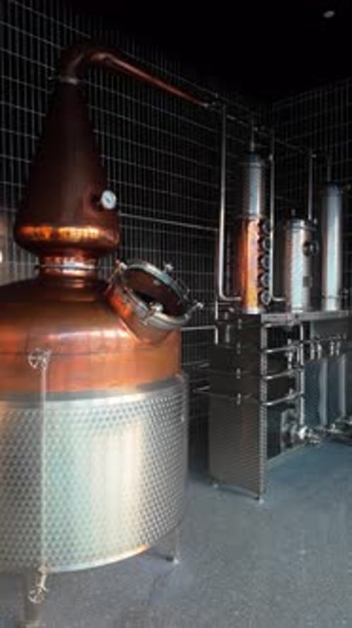 Copper Stills and Stainless Steel Condensers in Modern Craft Distillery Production Room Shiny Tanks