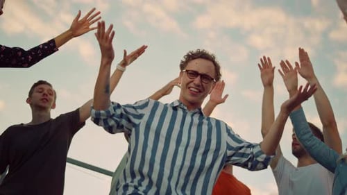 Cheerful Group Dancing Together with Raised Hands Outdoors