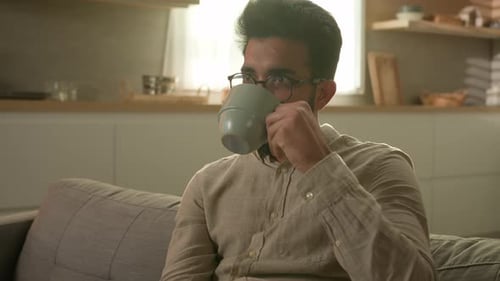 Man Relaxing on Couch Drinking Coffee at Home