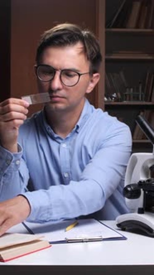 Vertical Video Scientist Examining Microscope Slide in Laboratory Setting