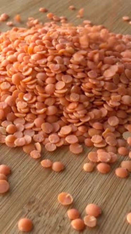 Red Lentils Falling in Slow Motion on Wood