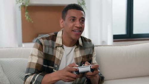 Man Playing Video Game Indoors on Couch