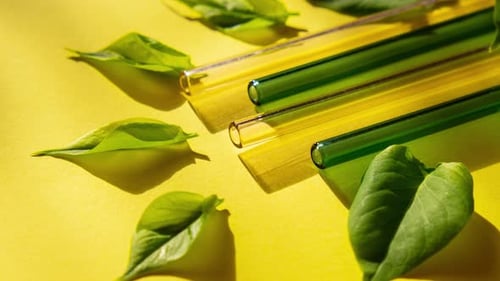 Acerque las pajitas de vidrio reutilizables sobre fondo colorido con hojas verdes en una bolsa ecológica ecológica