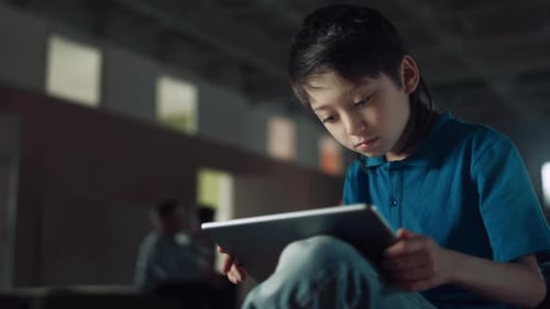 Focused elementary age boy surfing internet using tablet computer close up
