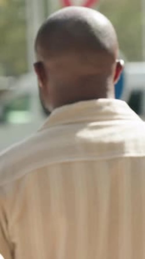 Vertical video: Checking traffic bald man in cream shirt walking curb, arrow and yield signs