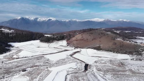 Slow Aerial ascending over snow covered mountain forest plains sunny Winter Day