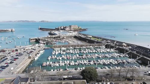 Flight over roof tops of St Peter Port Guernsey out over harbour to Castle Cornet with views of Herm