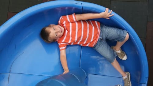Portrait Of Boy On Slide At School Playground