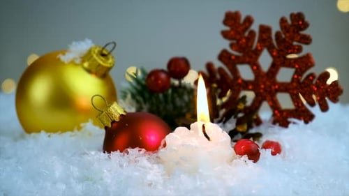 Christmas Ornaments and Candle on Snowy Background