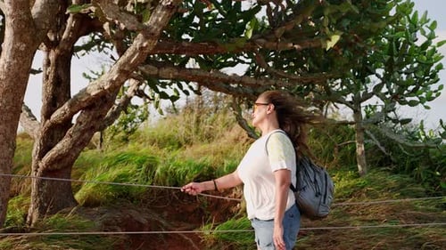 Mulher asiática sênior com óculos de sol sente alegria na rica vegetação ao pôr do sol. O cabelo ondula livremente na brisa