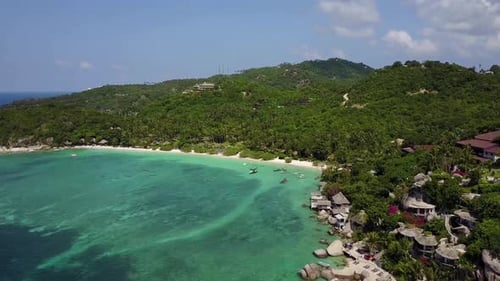 Aerial view at tropical island. Camera moves forward from coastline deep into the island. Bright sun