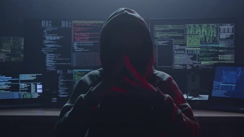 Un misterioso hacker rodeado de entornos oscuros y varias pantallas