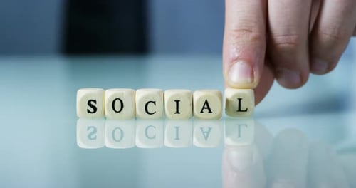 Hand Places Wooden Blocks to Spell Social