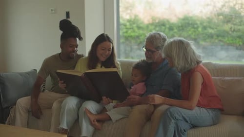 relaciones en una familia multiétnica: hija y su joven esposo viendo un álbum de fotos con un pariente