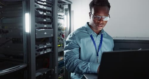 Man Working on Laptop in Server Room