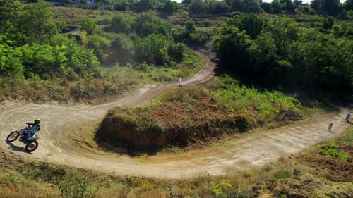 Aerial drone view of motorcyclists at a motocross race, mud track, rally motorcycles, greenery aroun