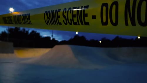 Yellow crime scene tape in front of a evening or night skatepark with blue stormy sky, street lights