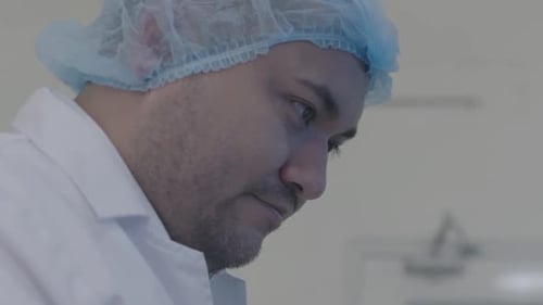 vue rapprochée d'un chercheur portant une casquette d'hôpital, profondément concentré sur le processus et la qualité