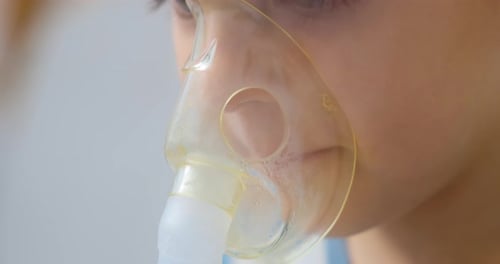 Child Wearing Nebulizer Mask in Hospital Close-up