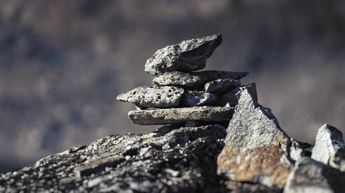 A stone cairn made of dark jagged pointy rocks in the gloomy mountainous landscape. Parallax video.