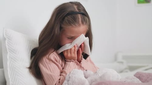 Little Girl Blowing Nose in Bed, Close Up