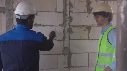 Construction Workers Discussing Plans in Unfinished Building