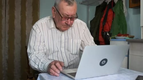 Senior Man Using Laptop at Table Indoors