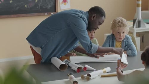 School Teacher and Two Little Boys Making Paper Craft Together