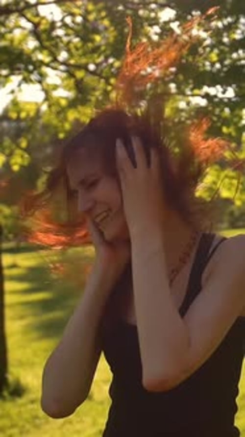 Vertical of Beautiful Redhead Girl with Long Hair Enjoys Music