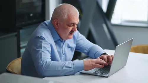 Senior Man Typing on Laptop at Home