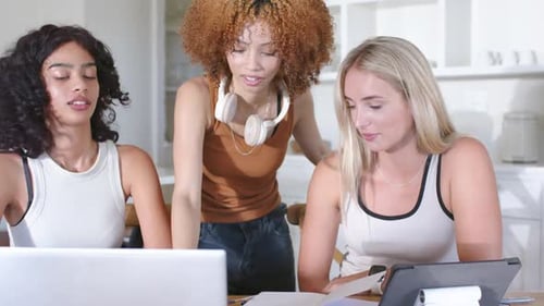 Diverses amies penchées à une table en bois, date limite, exhortant une femme debout à pointer un stylo sur un ordinateur portable