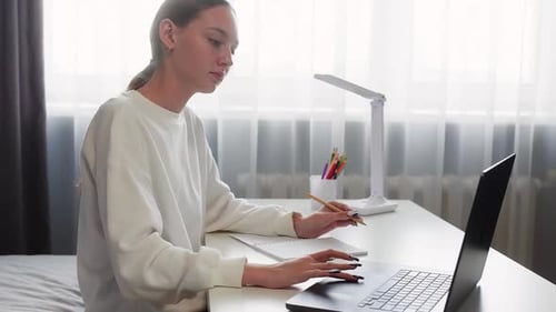 Young Woman Typing on Laptop at Desk