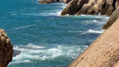 Ocean Waves Wash Over the Rugged Rocky Coastline on a Sunny Day