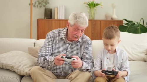 Grandfather and Grandson Playing Video Games Together at Home