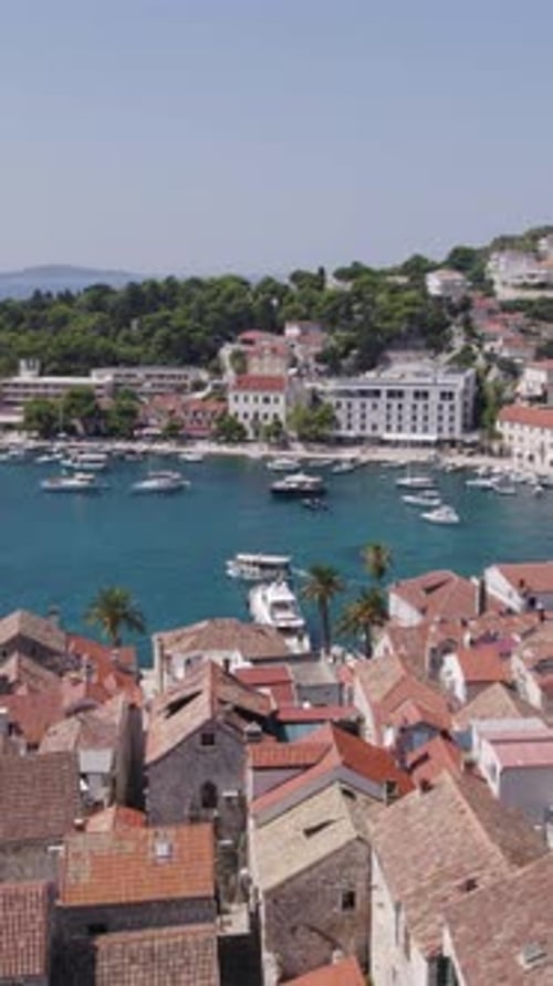 Aerial view of Hvar town, Croatia, showing harbor with boats and red roofs. Vertical Video
