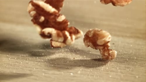 Walnut Halves Falling onto Wooden Surface in Slow Motion