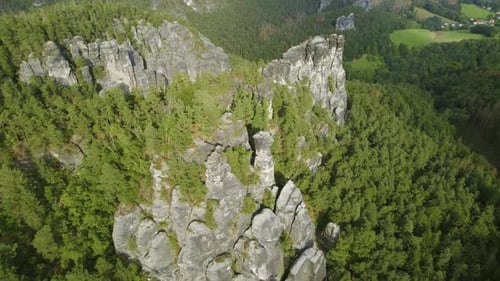Natural rock formations surrounded by verdant trees and hills in mountain coniferous forest.