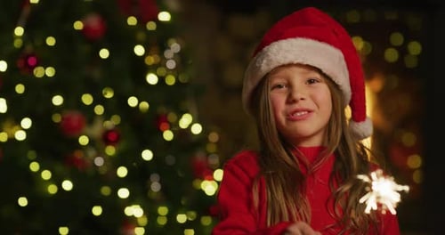 Smiling Girl Holding Sparkler in front of Christmas Tree