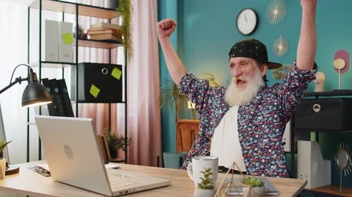 Senior Man Celebrates Success at Computer in Home