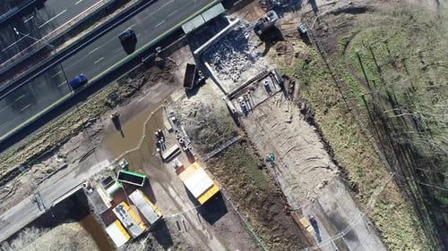 Drohnenaufnahme einer Baustelle neben einer Autobahn, man kann Leute sehen, die auf der Autobahn fahren.