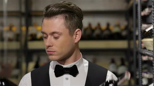 Young Adult Sommelier Examining a Bottle of Wine