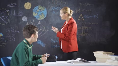Teacher Explains Science to Student at Chalkboard