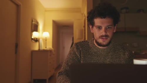 Man Works on Laptop and Drinks Coffee Indoors