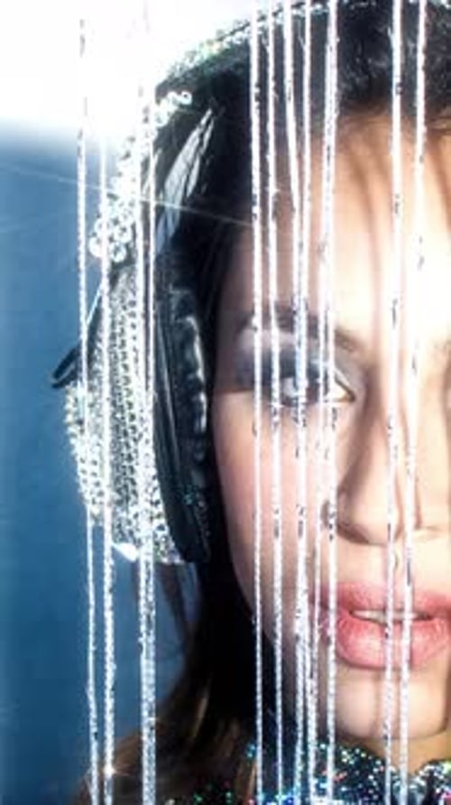 Woman Wearing Sparkly Headphones in Front of Beads