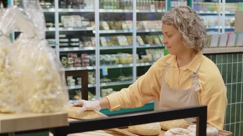 Supermarket Worker Laying Out Fresh Bread on Shelves