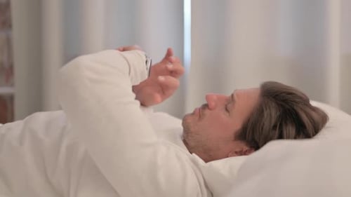 Man in Bed Uses Smartwatch Technology