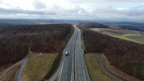Aerial footage of a highway through the forest with lots of traffic, 4k